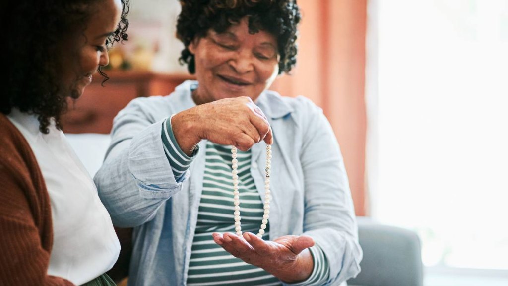 Gifts for Mother's Day: Shot of a young woman giving her elderly relative a present on the sofa at home -
