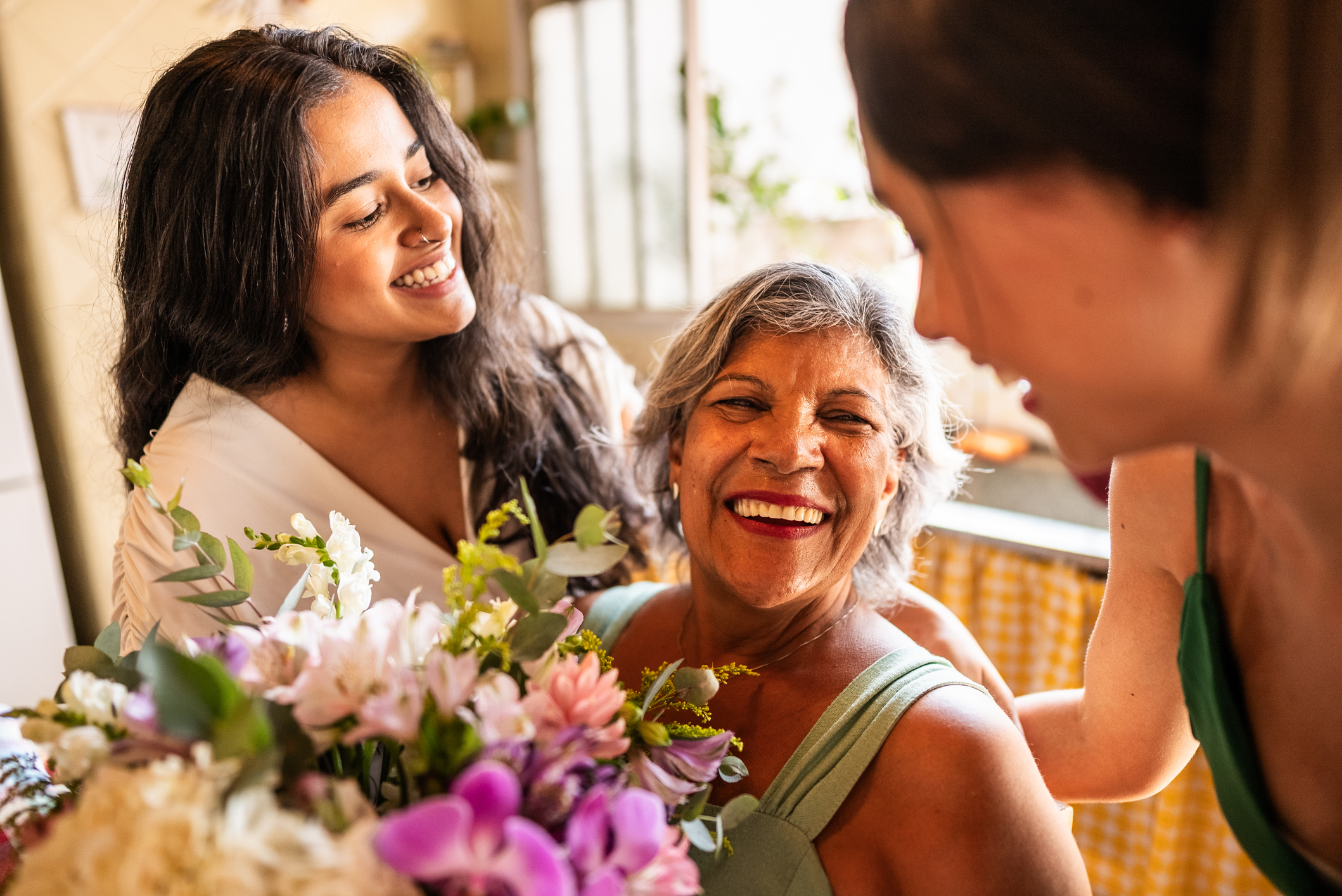 Young sisters giving flowers to grandmother at home
