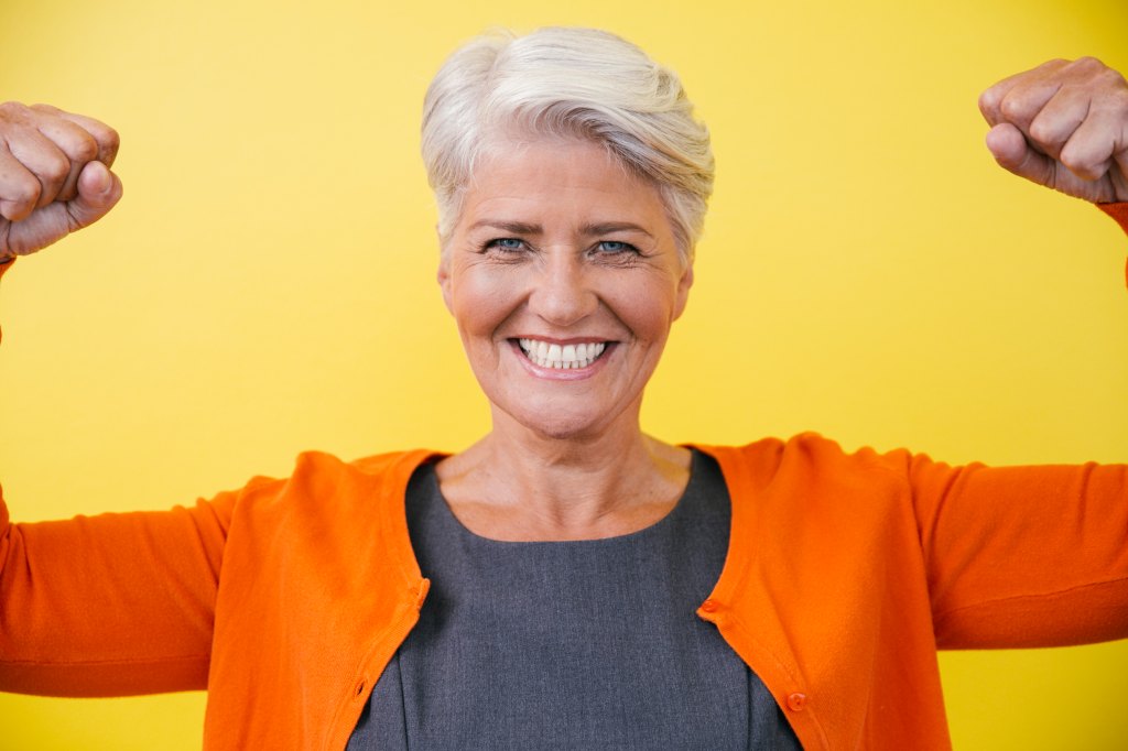 Woman flexing her arms in a power pose, overcoming imposter syndrome
