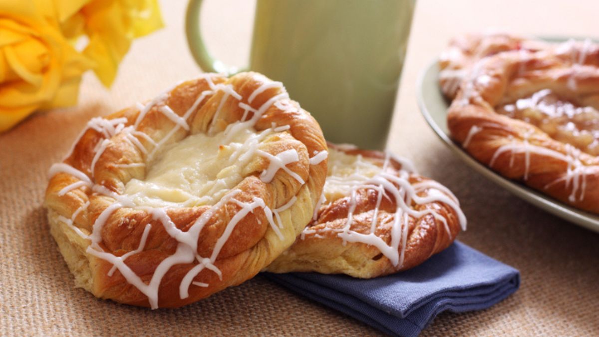 cheese danishes with frosting on table with napkin and mug