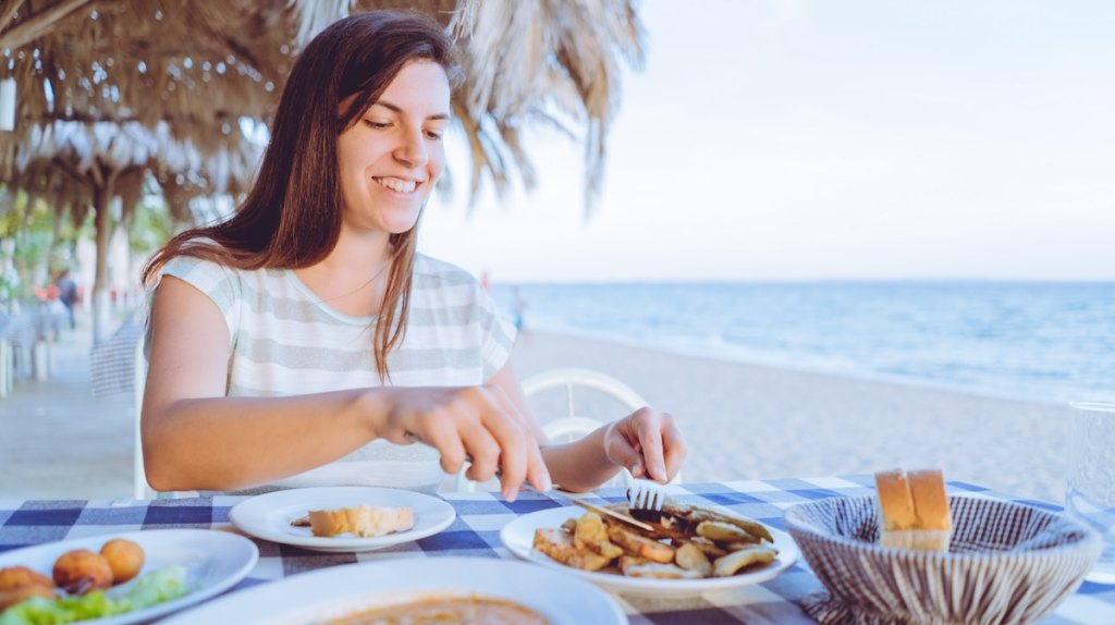 A young woman dines by the sea.
