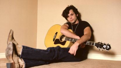 man sitting with guitar; john mellencamp greatest hits