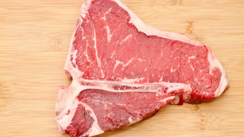 A slab of raw beef on a cutting board.