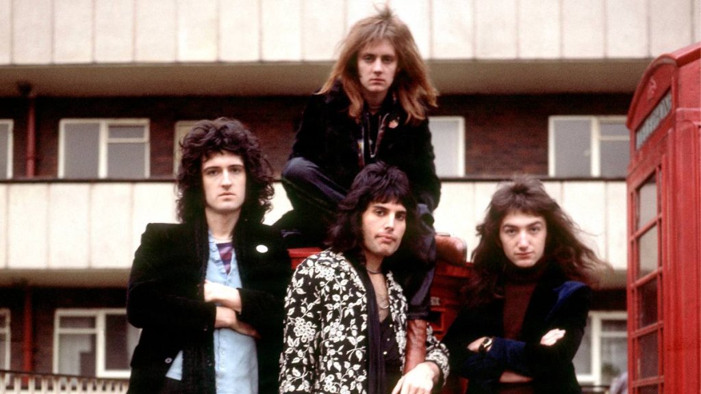 group of men sitting on instruments; queen music catalog