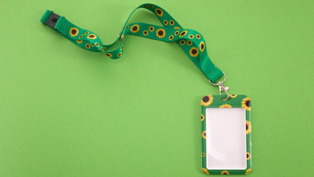 A vibrant green lanyard with sunflower motifs and an empty badge on a green background.