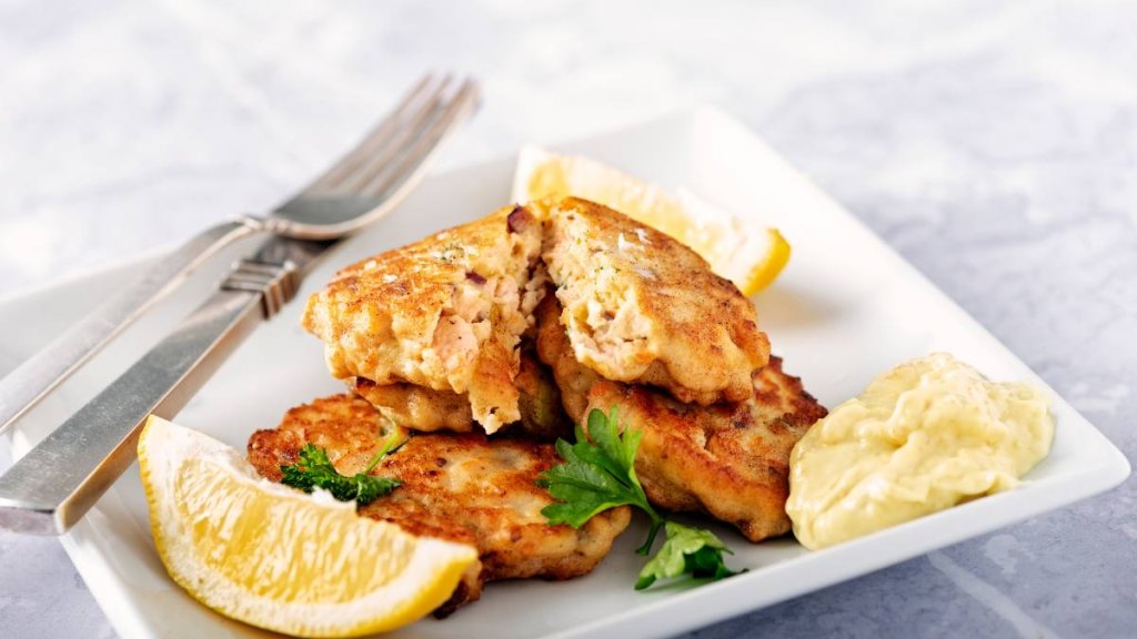 the keto diet: Traditional Danish Fiskefrikadeller or fish cakes. Fiskefrikadeller are made from finely chopped white fish, usually cod or haddock, with small pieces of more roughly chopped salmon added, along with cream, onion, carrot and flour, salt and white pepper. Served with slices of lemon and remoulade. Colour, horizontal with some copy space.
