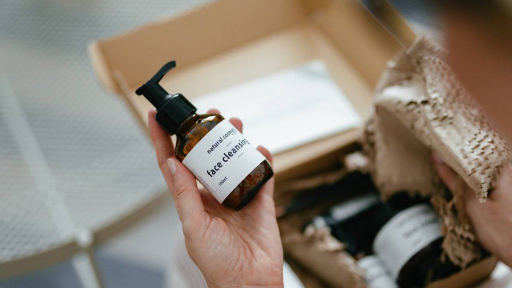 father's day gifts: Anonymous woman holding a carton gift box on her knees. There are various natural beauty cosmetics products inside and a personal paper note.