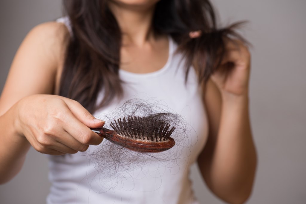 woman brushing hair and showing hair loss