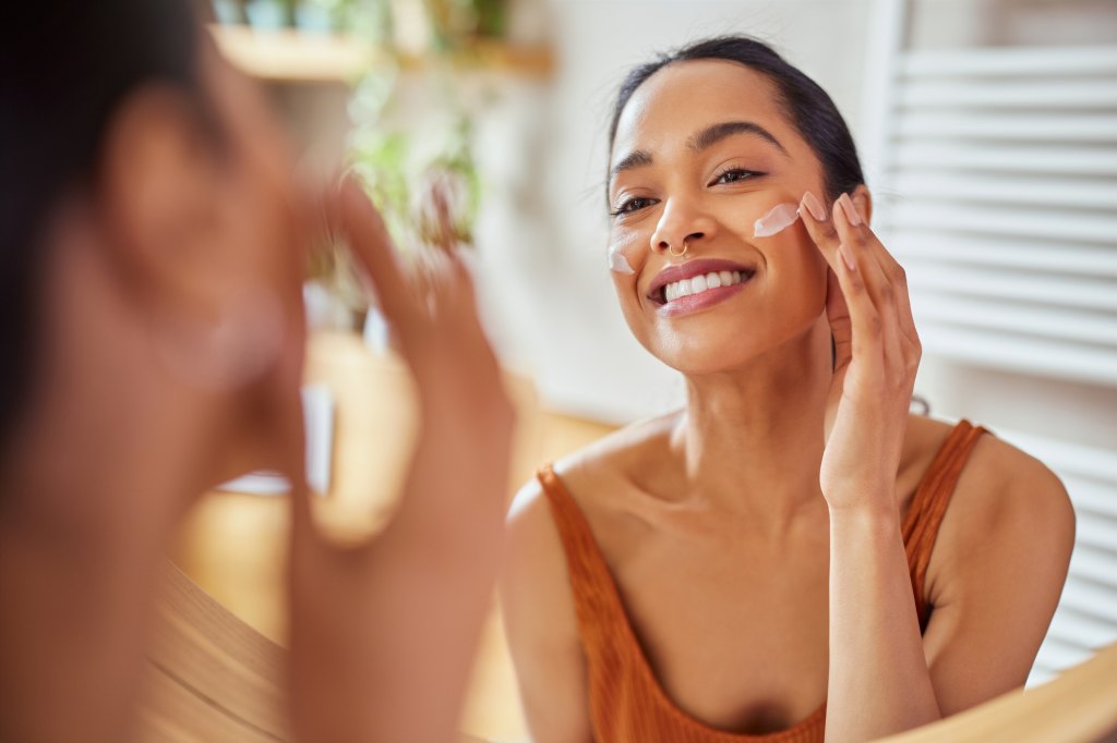 woman smiling applying sunscreen to face