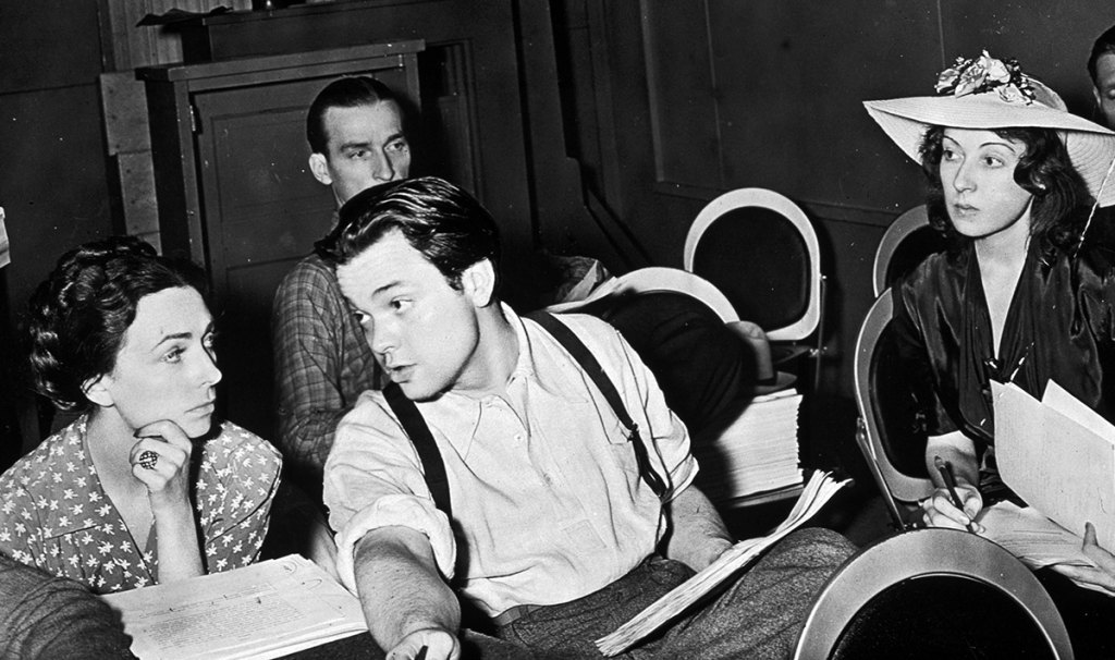 1938, American actor, writer, producer and director Orson Welles talking with Agnes Moorehead on a theatre stage with members of the Mercury Theatre.