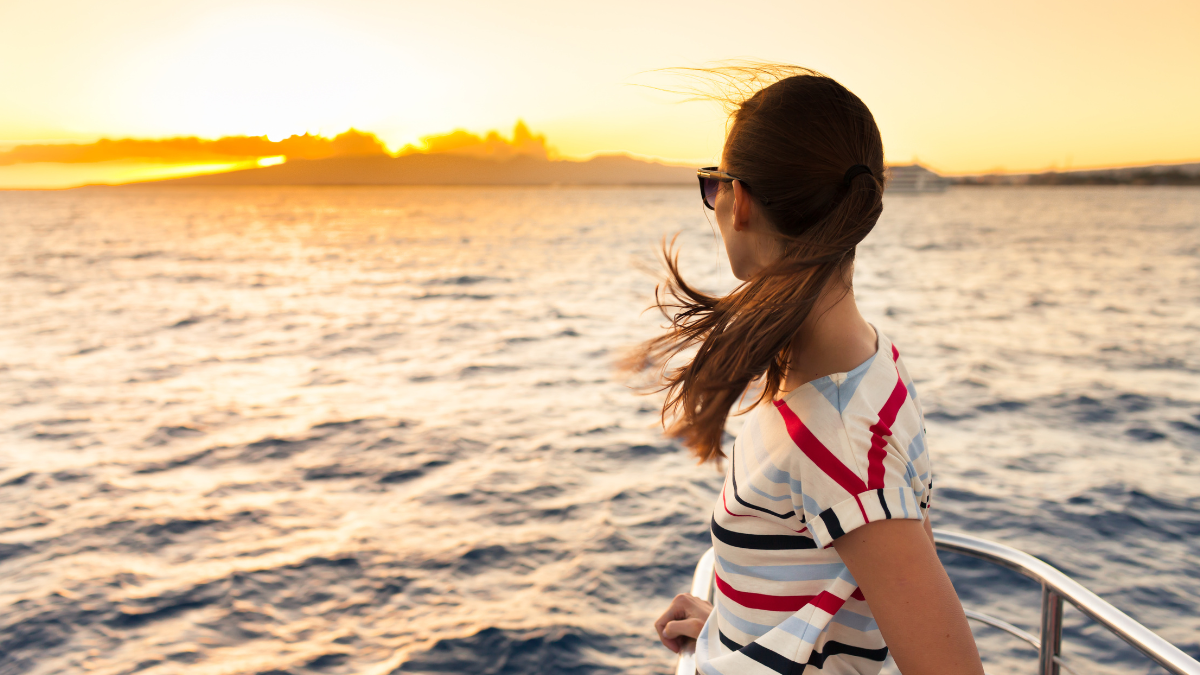 Young woman looks at ocean from cruise ship
