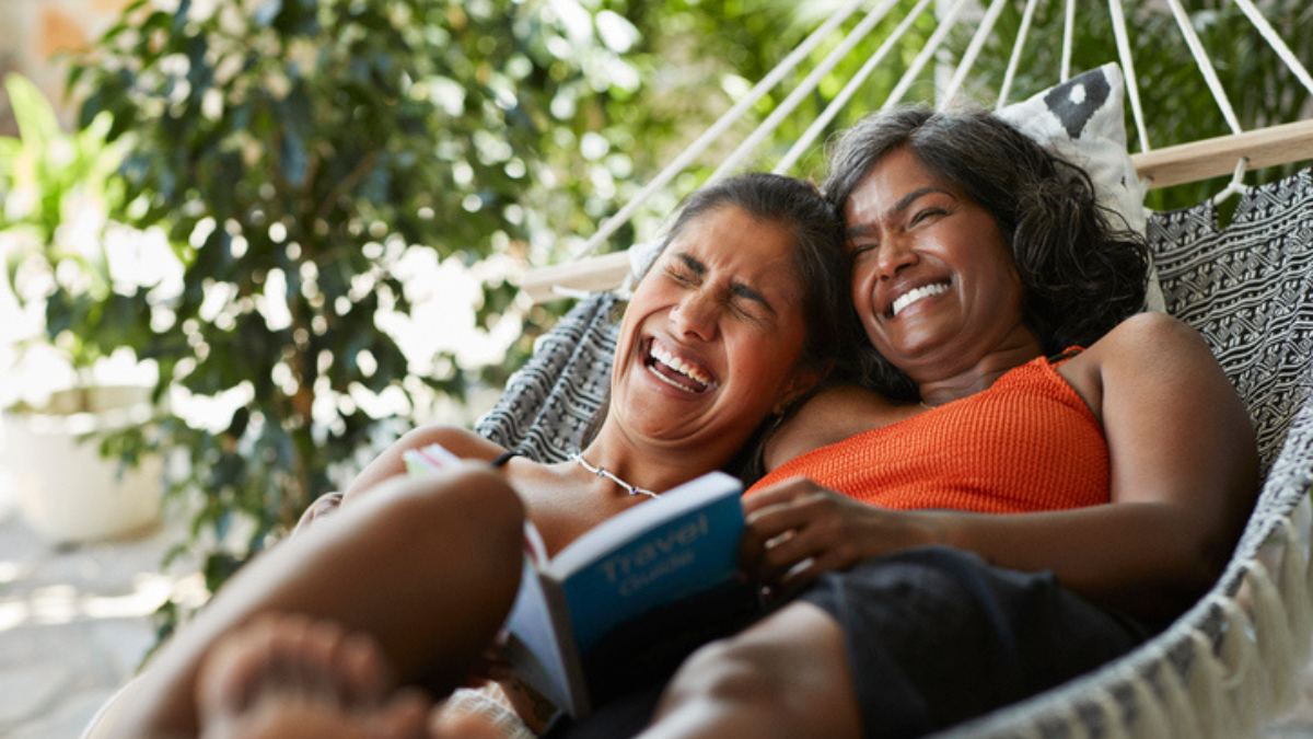 Two women laughing together on a hammock
