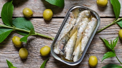 Open can of sardines in olive oil on rustic table