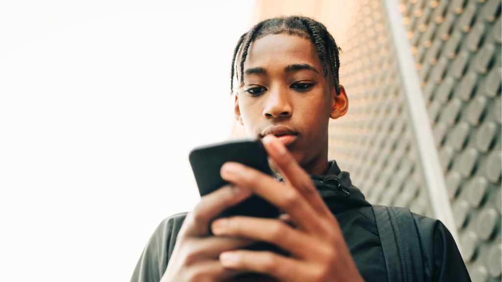 Teen boy looks down at his phone