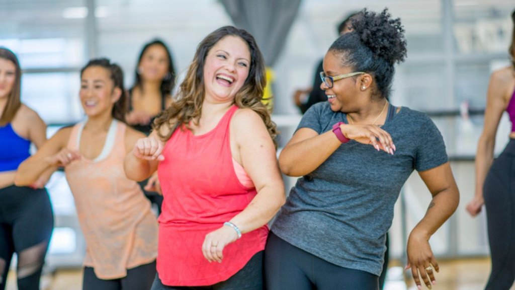 smiling mature women practicing social prescribing in a group dance class in a studio