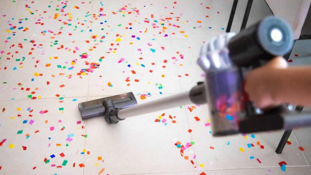 Cleaning home floor with vacuum after party with confetti (fourth of july stains)