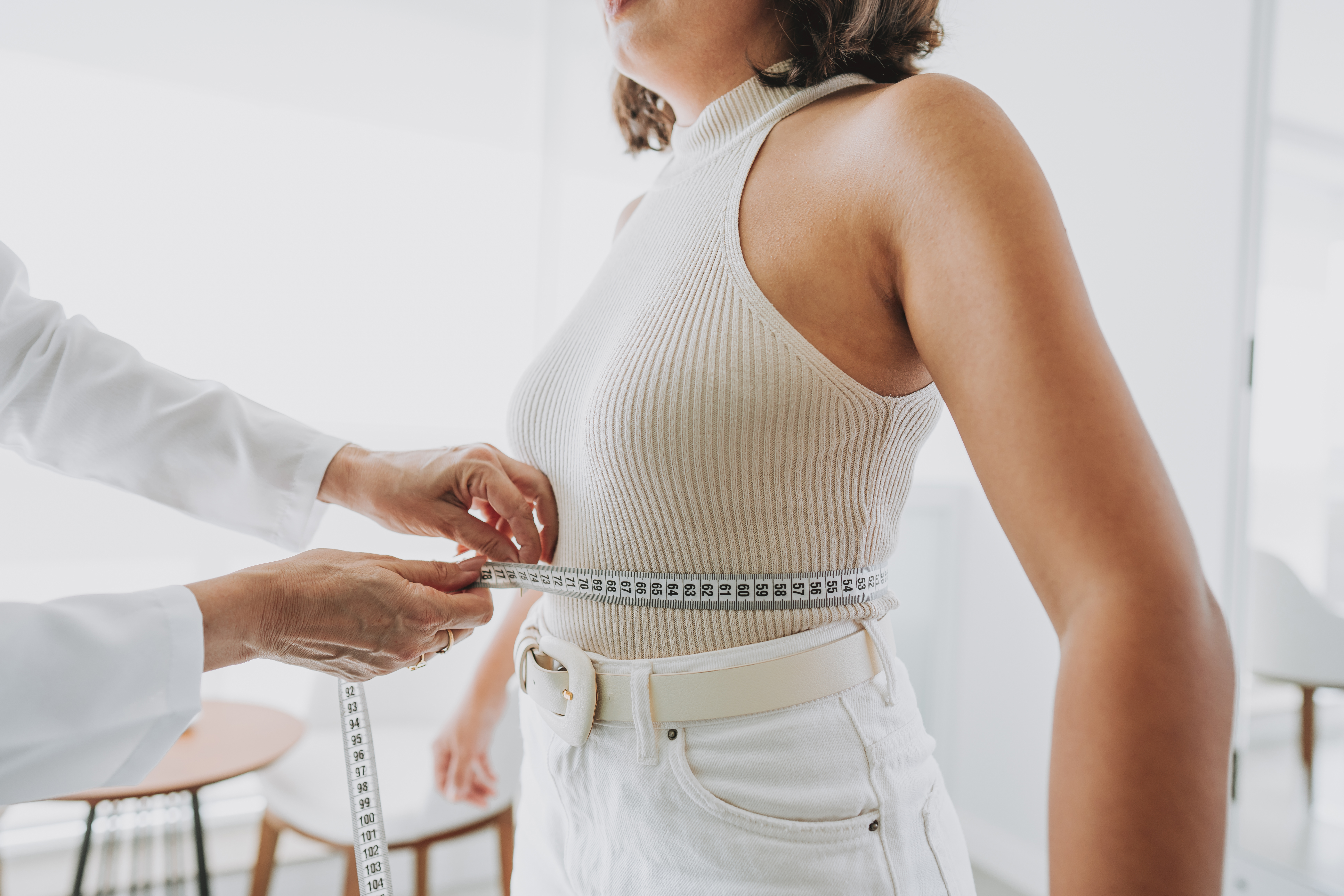 Woman having her midsection measured by medical professional to calculate her body roundness index score
