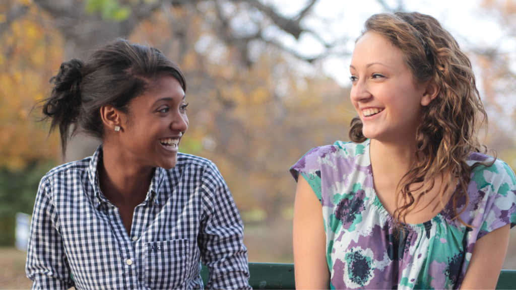 Two young girls talking and smiling outside