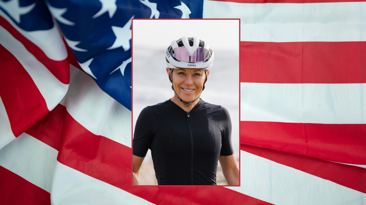 Olympic cyclist Mari Holden poses with helmet on in front of American flag