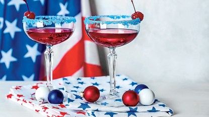 red martini in blue-rimmed glass with american flag in background