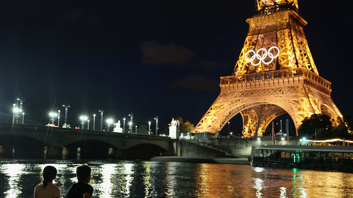 Spectators view the Eiffel Tower and Olympic rings along the Seine river on July 21, 2024 in Paris, France. The city is gearing up to host the XXXIII Olympic Summer Games from July 26 to Augusst 11: are they swimming in the seine
