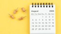August calendar is used to plan daily work and life with a push pin on a yellow paper background.