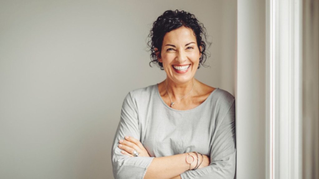 mature woman smiling with reduced stress, one of the benefits of reading