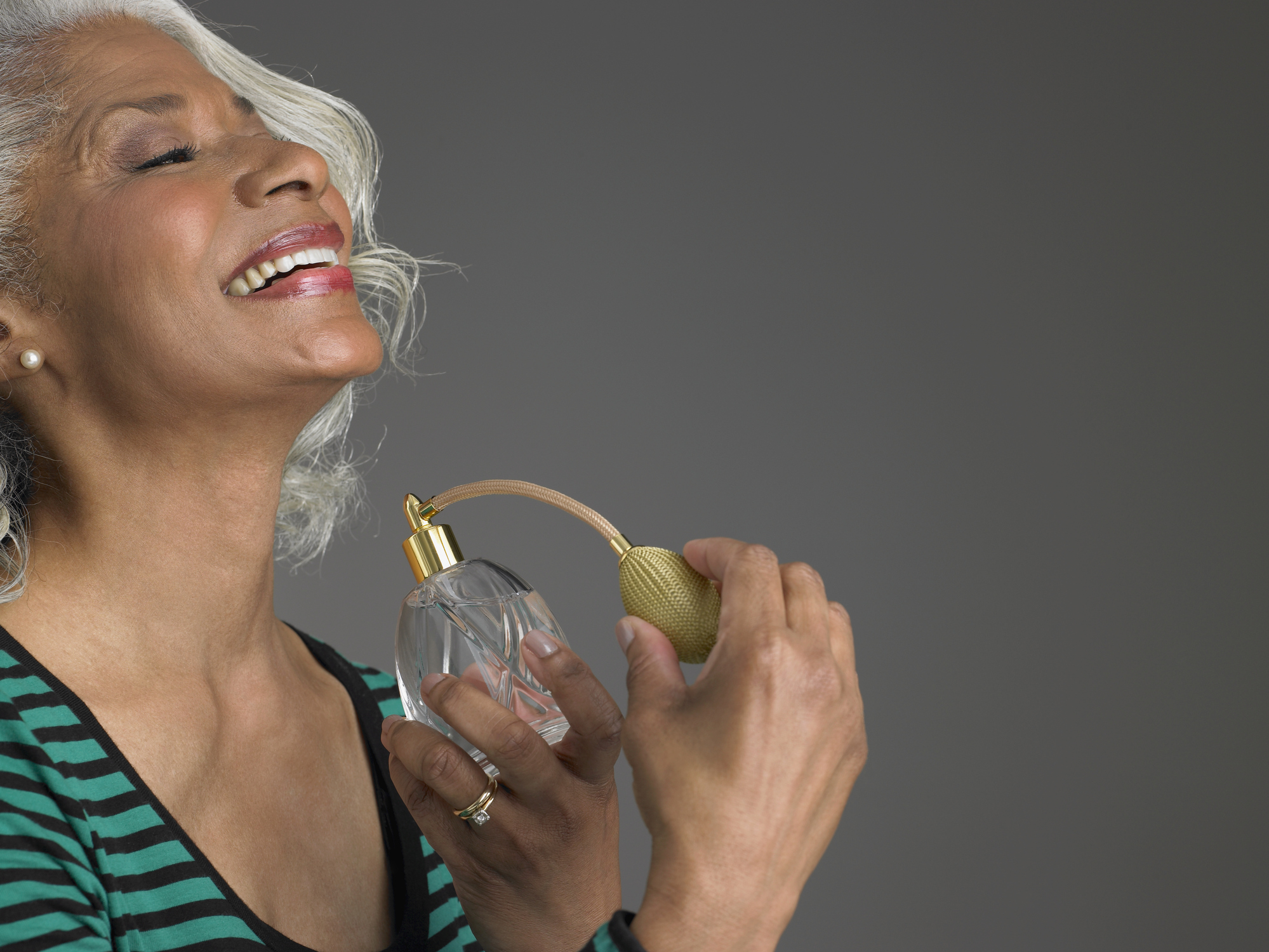 mature woman spraying perfume