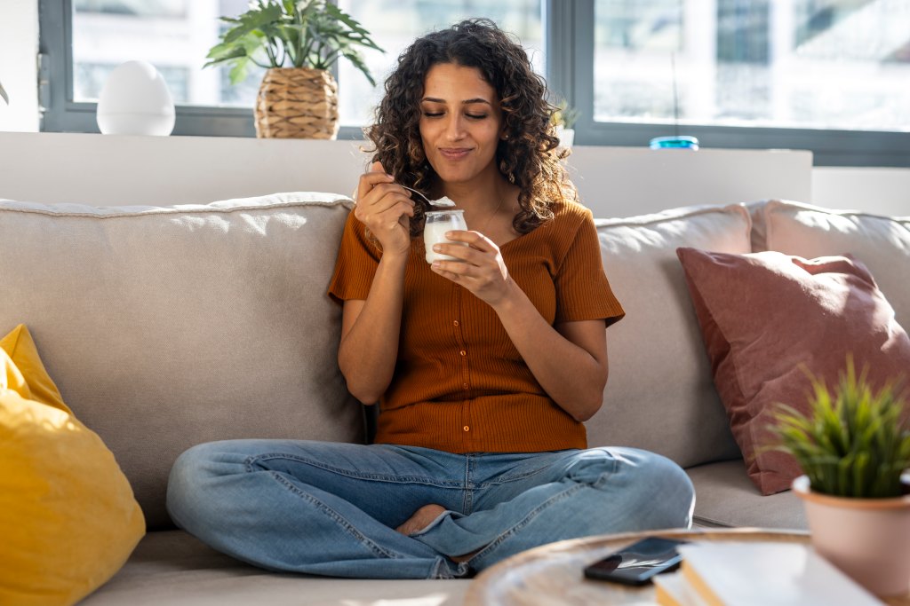 woman sitting on couch eating yogurt