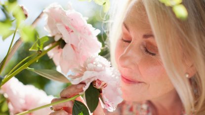 senior woman smelling pink flowers, concept for aromatherapy for long covid