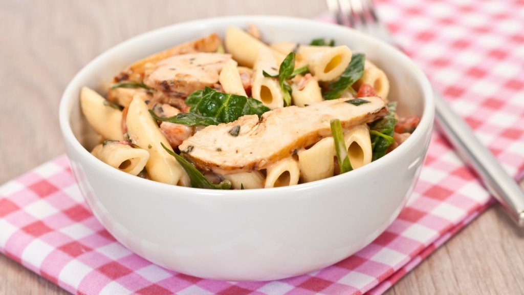 a bowl of chicken and pasta, which is a treatment option for traveler's diarrhea, on a red check napkin