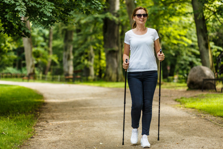 Mature woman walking outside with walking sticks for joint pain