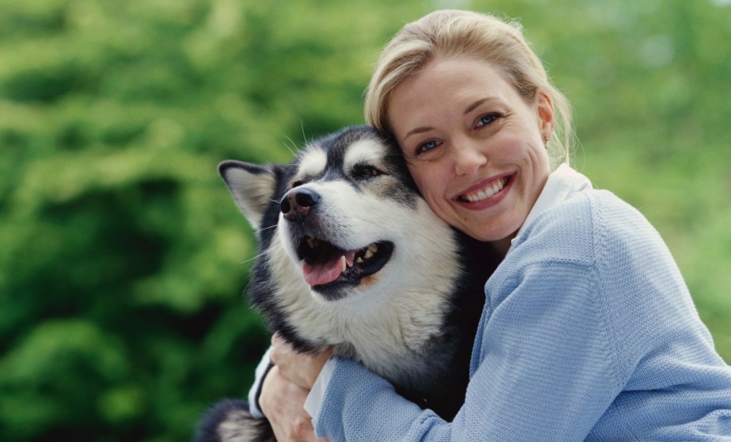 Woman cuddling a dog to lower her blood pressure
