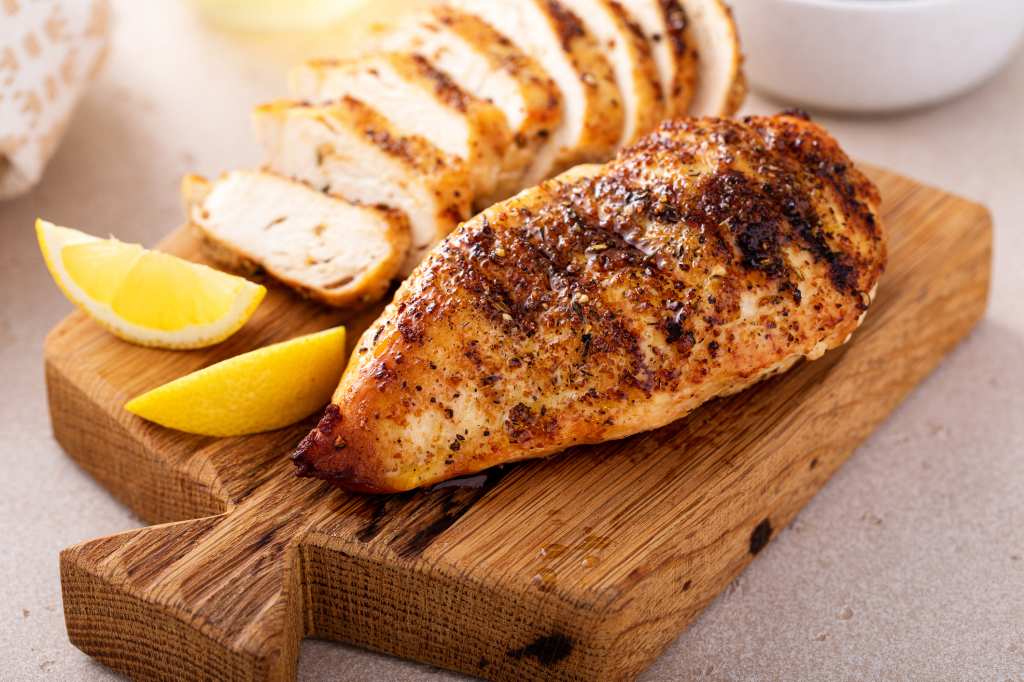air fryer chicken breasts sliced on wooden cutting board with lemon
