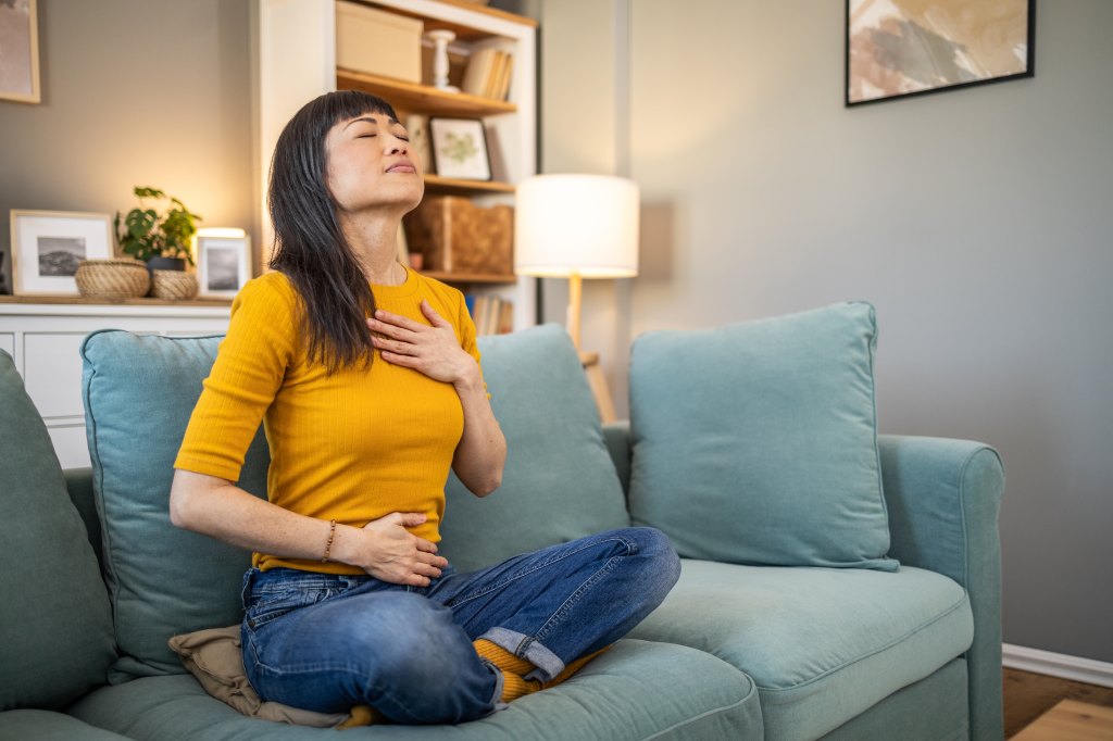 woman practicing meditation and deep breathing at home
