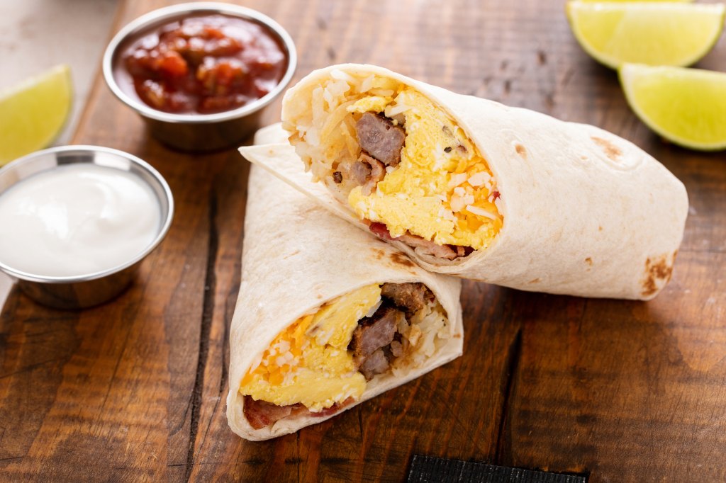 breakfast burrito halves on wooden board