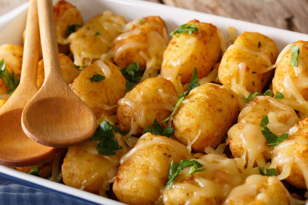 close up of baked Tater Tot Hotdish with wooden serving spoons