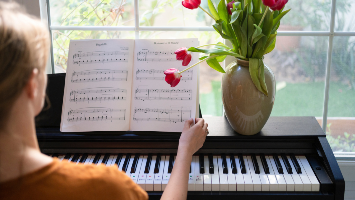 back of woman turning sheet music to play piano
