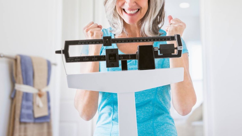 Woman celebrating weight loss on scale after following the soup and shake diet