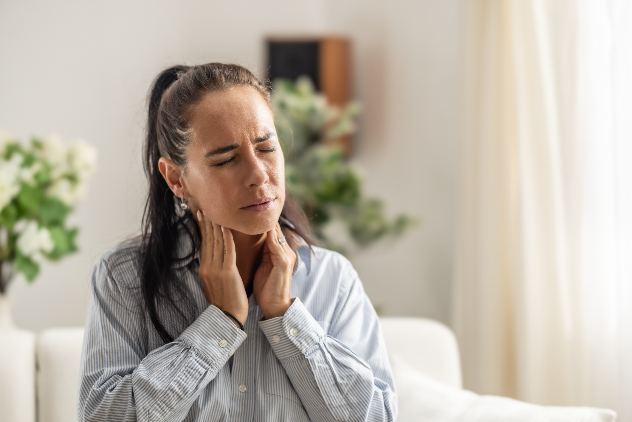 mature woman feeling her neck for thyroid nodules