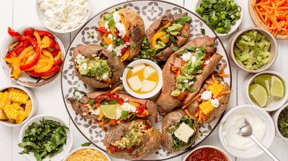 A baked potato bar with various toppings and fillings