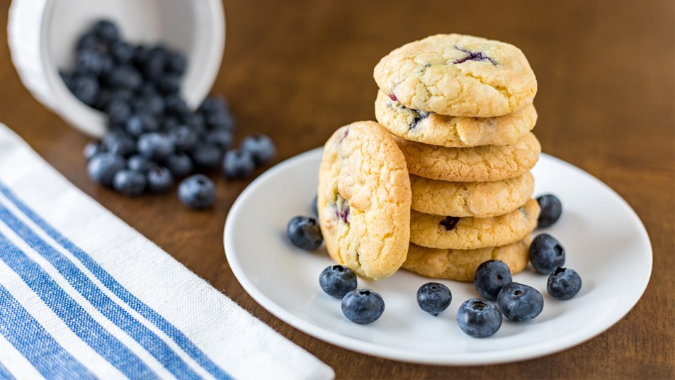 A stack of blueberry cookies with fresh blueberries on the plate