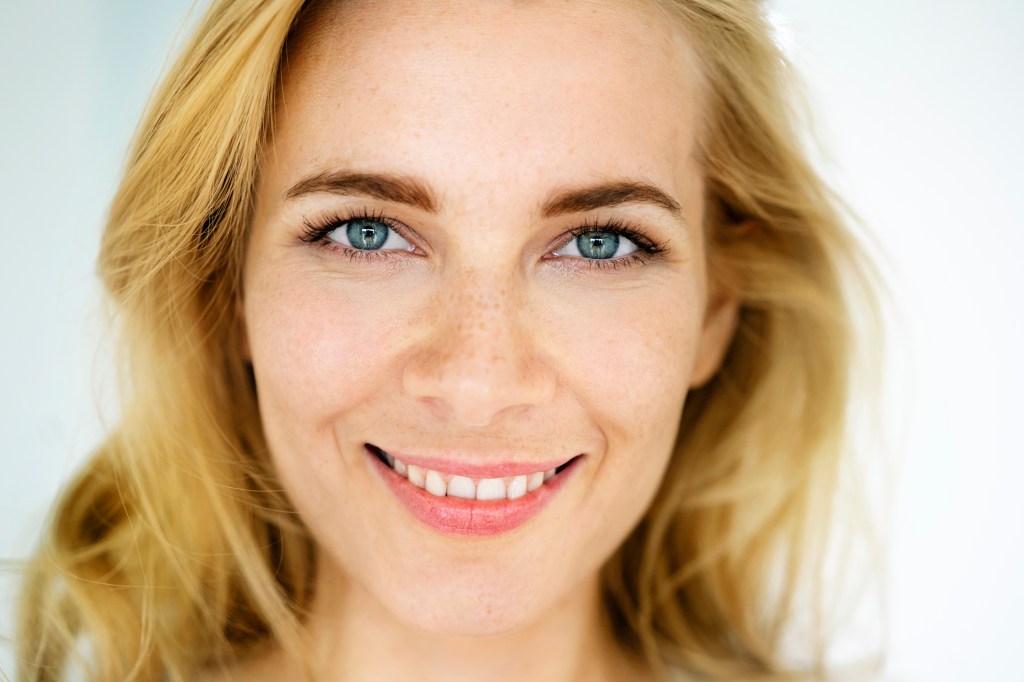 Photo of a blond-haired woman who is smiling and has voluminous eyelashes