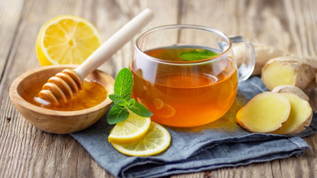 A glass cup of tea with honey, ginger and lemon