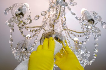 woman's hand in gloves cleaning a chandelier