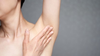 A close up of a woman touching her itchy armpit