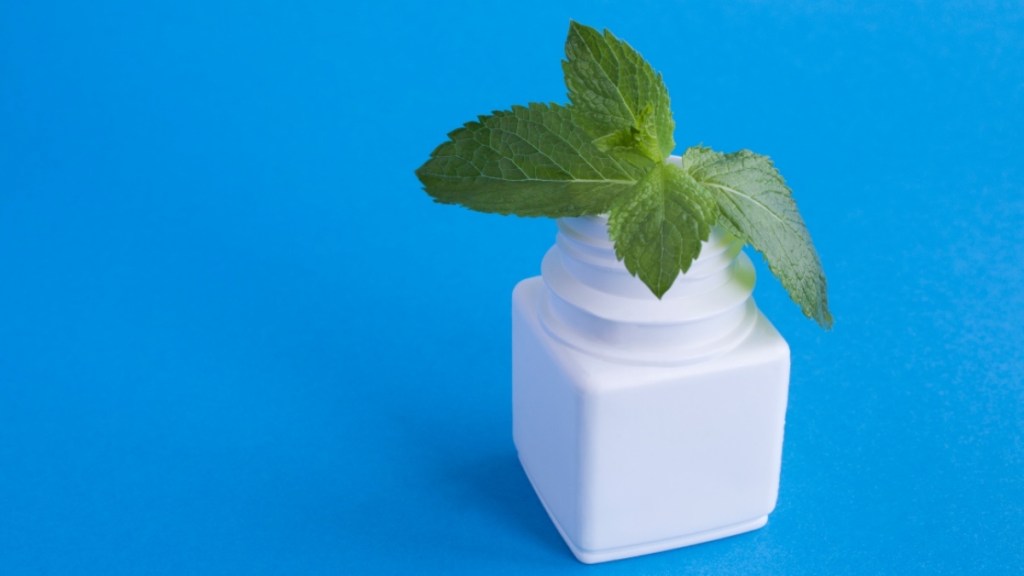 A sprig of mint in a white jar against a blue background, which can be used for itchy armpits