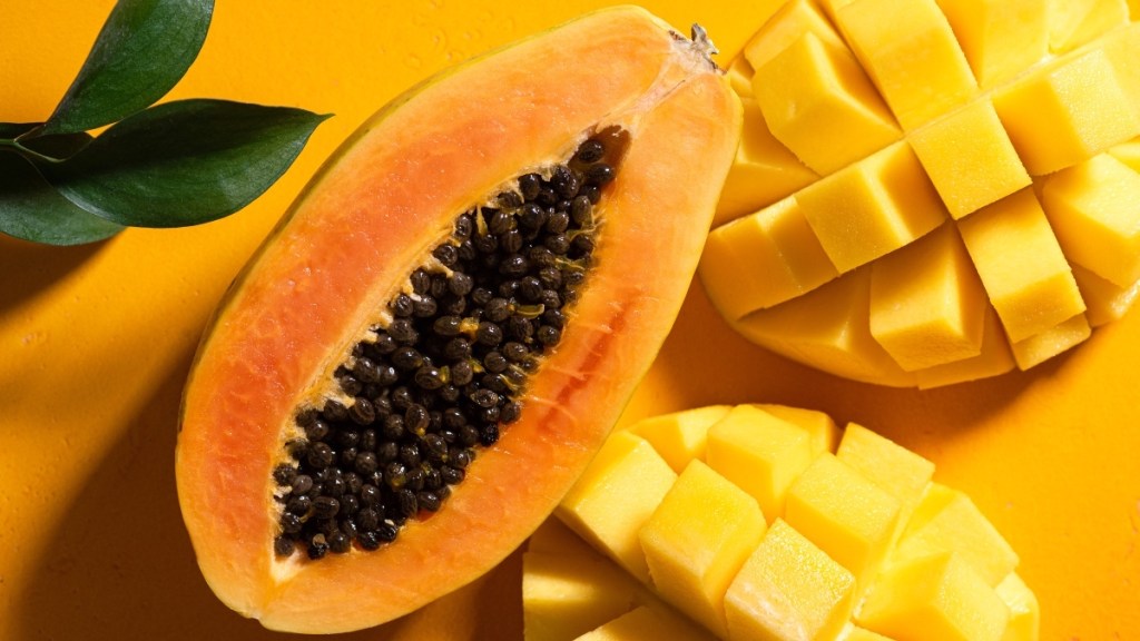 A sliced open papaya beside cubed papaya