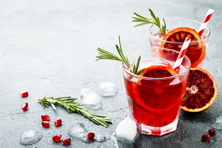two red cocktails with citrus and thyme