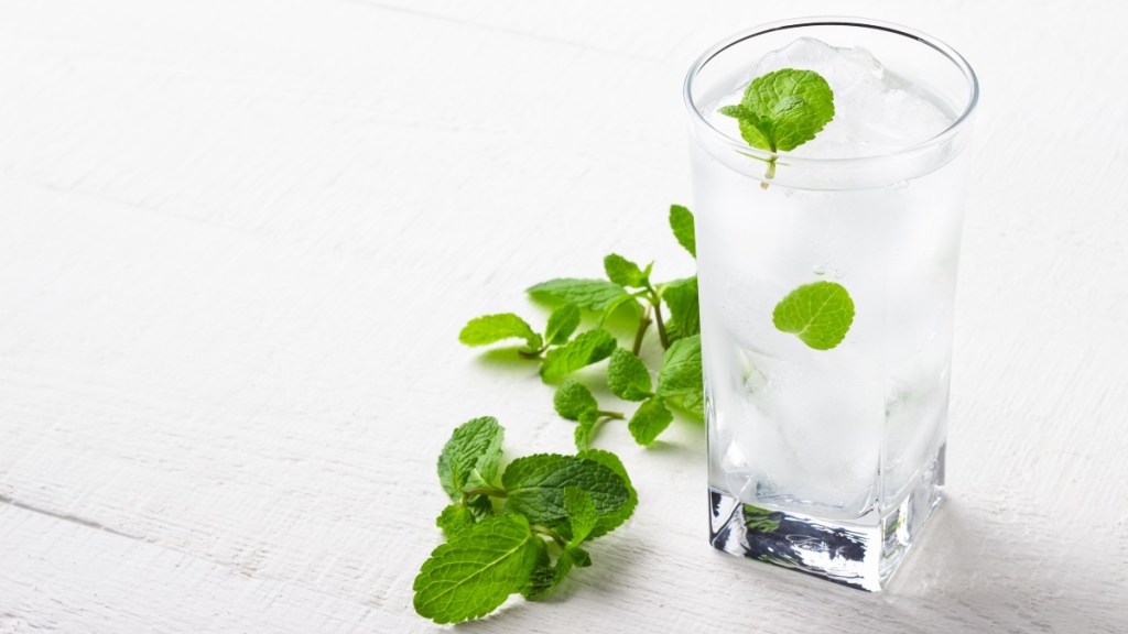 A clear glass of water with ice and mint, which can be used for dry mouth
